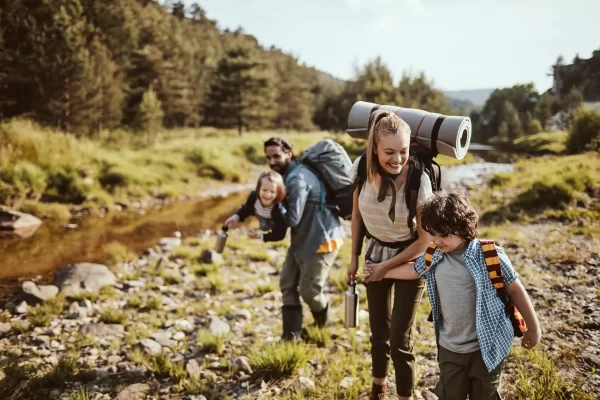 Famiglia che fa un'escursione lungo un sentiero di montagna vicino a un ruscello.